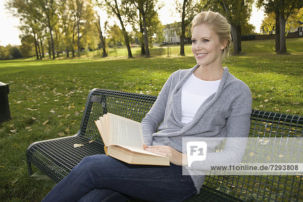 Europe  Germany  North Rhine Westphalia  Duesseldorf  Young woman reading book on park bench