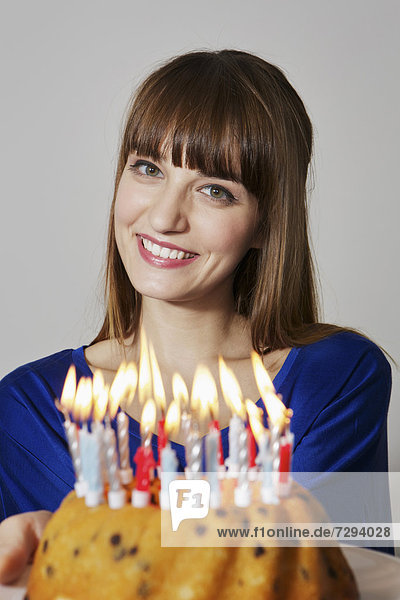 Young woman showing birthday cake,  smiling,  portrait
