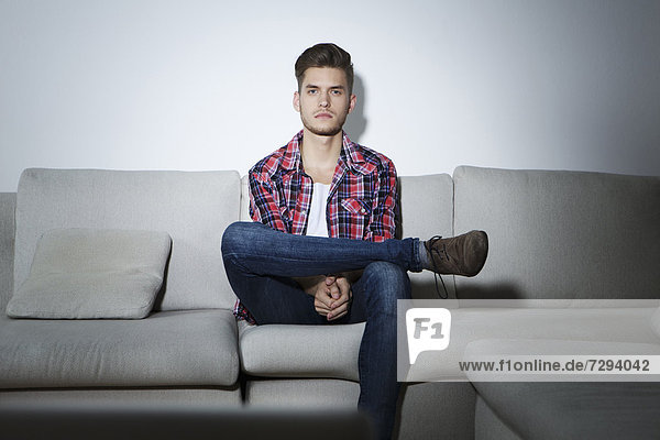 Young man sitting on couch in front of screen