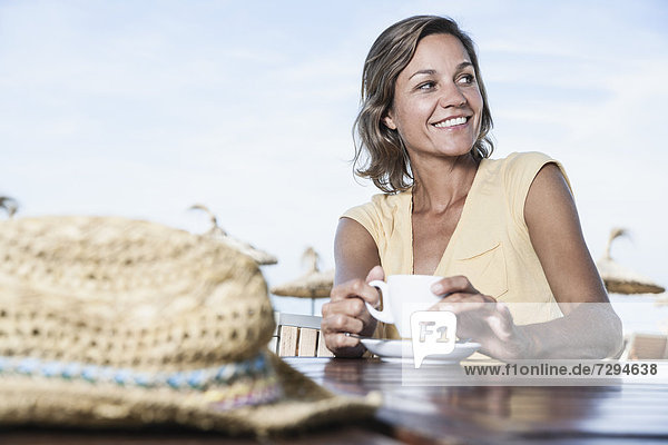 Spanien  Mittlere erwachsene Frau im Café mit Strohhut