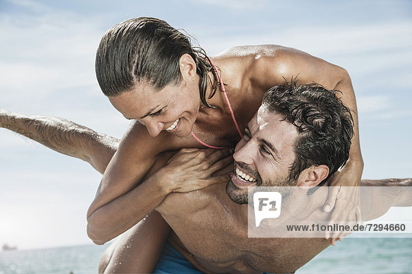 Spain,  Mid adult man giving piggy back ride to woman
