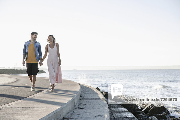 Spain,  Mid adult couple walking along coast