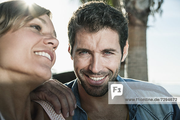 Spain  Mid adult couple sitting on bench  smiling