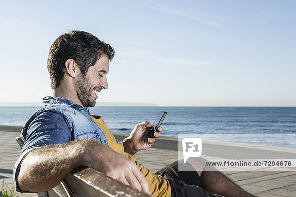 Spain,  Mid adult man using smart phone,  smiling