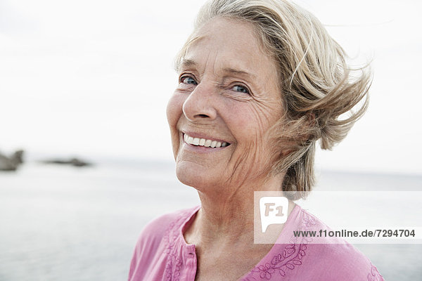 Spain  Senior woman smiling at Atlantic ocean