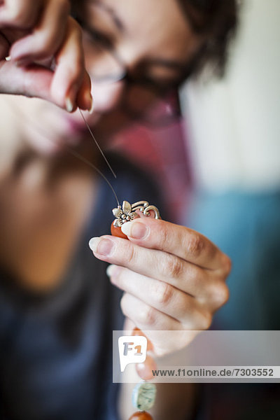 Mittlere erwachsene Frau die Perlenschmuck herstellt DIY