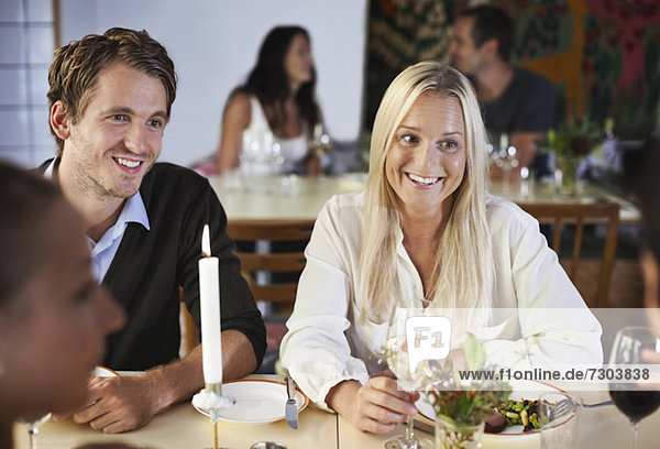 Glückliche Freunde am Restauranttisch mit Menschen im Hintergrund