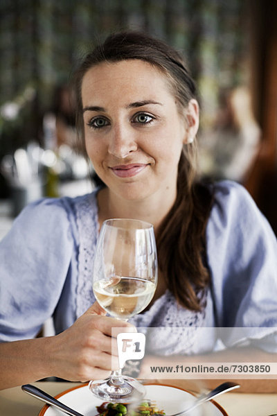 Young woman holding wineglass at restaurant table
