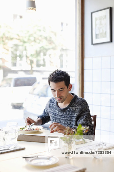Junger Mann am Restauranttisch mit digitalem Tablett