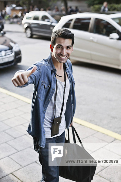 Portrait of happy young man gesturing as he carries duffle bag