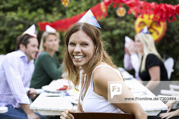 Porträt einer fröhlichen mittleren erwachsenen Frau  die mit Freunden im Hintergrund Krebspartys feiert.