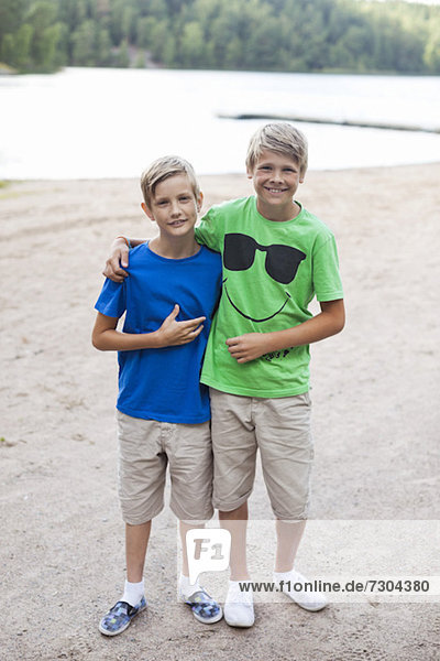 Portrait of happy brothers standing together on beach