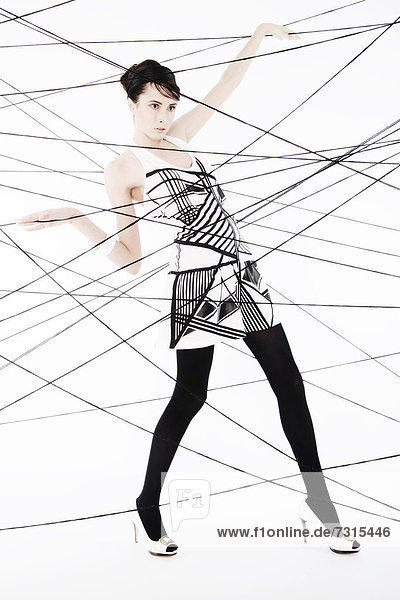 Woman  24  dressed in the style of the 60s  standing between spanned threads  symbolic image network
