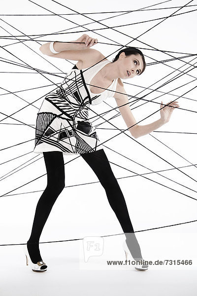 Woman  24  dressed in the style of the 60s  standing between spanned threads  symbolic image network