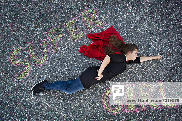 'Junge Frau scheint in Superman- oder Supergirl-Haltung zu fliegen  Schriftzug ''Supergirl''  von oben aufgenommen'