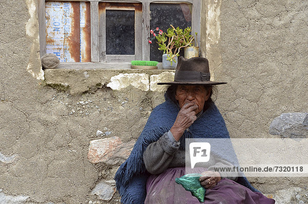 Indigenous woman chewing coca in front of her hut  La Paz  Altiplano  Bolivia  Andes  South America