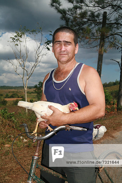 Man riding a bicycle carrying a chicken in his hands  Vinales  Pinar del RÌo Province  Cuba  Latin America