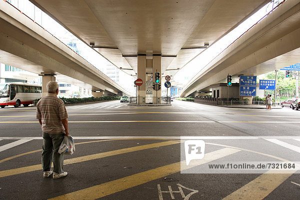 Mann wartet unter einen Autobahnaustausch in Shanghai  Shanghai Shi  Volksrepublik China  Asien