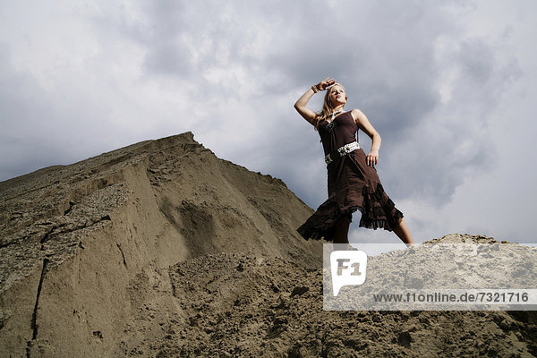 Frau steht auf einem Sandhügel