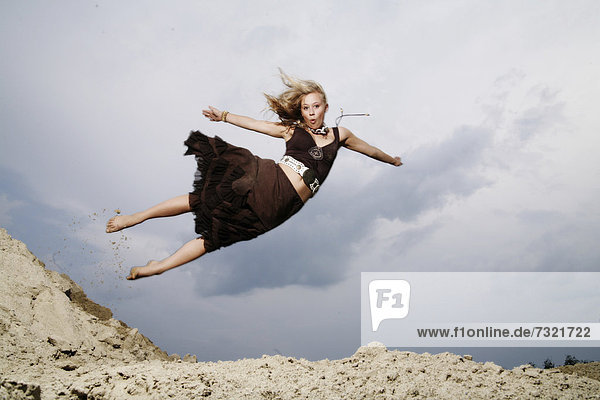 Woman jumping from a sand hill