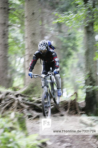 Downhill mountain biker riding on a trail through a forest