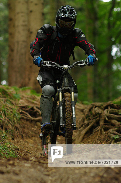 Downhill mountain biker riding on a trail through a forest