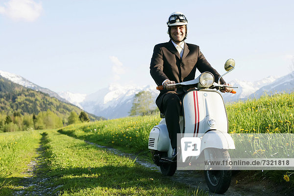 Businessman  29  on a classic motor scooter  Allgaeu  Bavaria  Germany  Europe