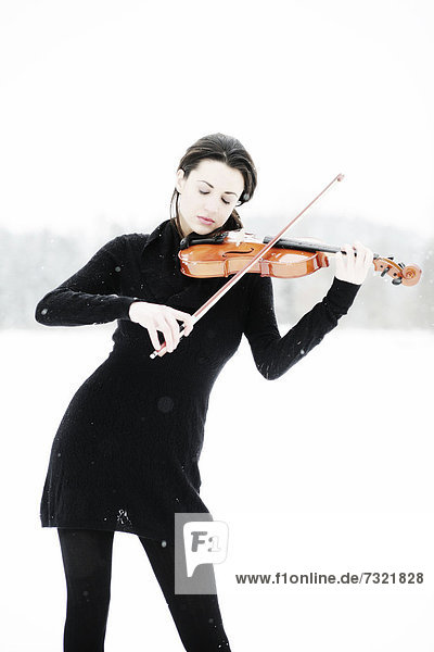 Frau  19 Jahre  mit Geige in verschneiter Winterlandschaft