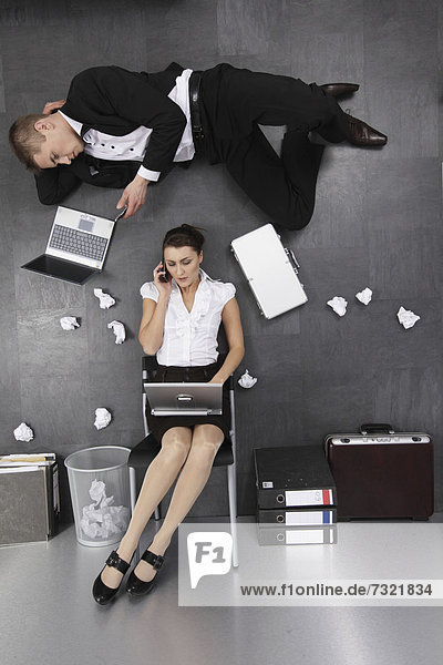 Geschäftsfrau und Geschäftsmann in Aktion auf dem Boden  in irritierender Perspektive
