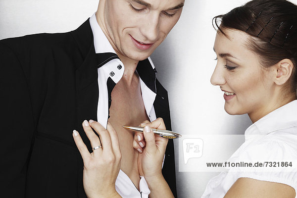 Geschäftsfrau schreibt auf der nackten Brust eines Geschäftsmanns  Symbolbild Liebe im Beruf