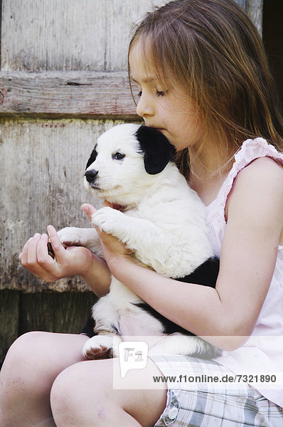 Mädchen spielt draußen mit jungem Hund