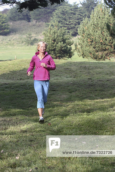 Young blonde woman outdoors. Jogging in countryside.