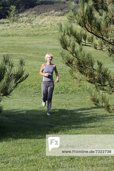 Blonde woman outdoors. Jogging in countryside.