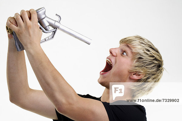 Junger Mann hält Zapfpistole vor offenen Mund