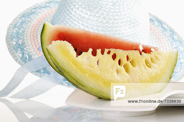 Melonenspalten auf Teller vor Sonnenhut  Symbolbild Ferien im Süden