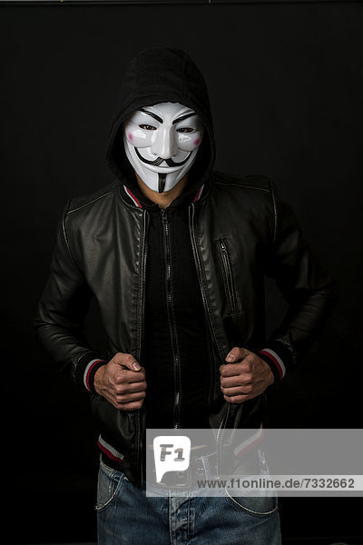 Young man wearing an anonymous mask with a hood and a black leather jacket