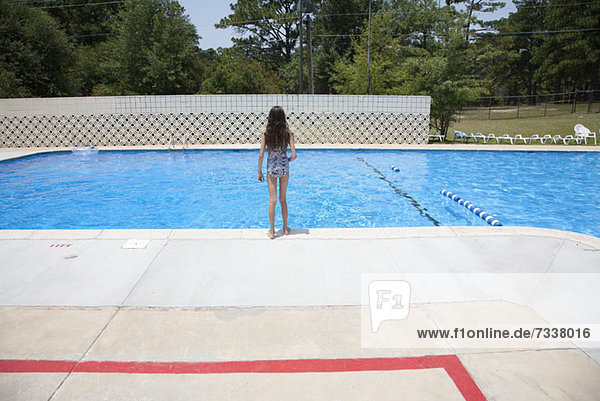 Ein Mädchen steht am Rande eines Swimmingpools.
