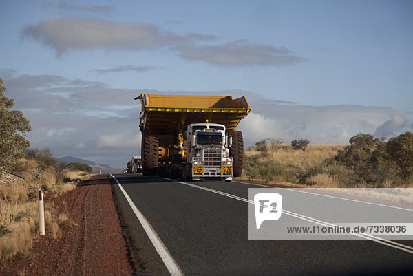 Ein Lastwagen mit breiter Ladung fährt auf einer Wüstenautobahn.