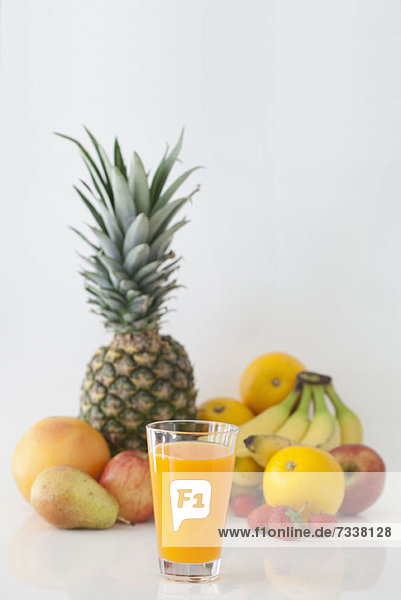 Glas Orangensaft mit den fruchtigen Zutaten im Hintergrund