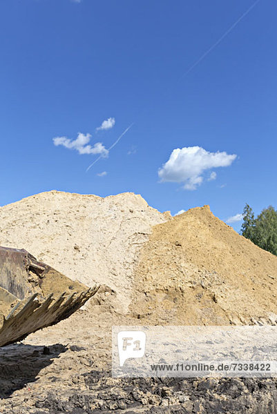 Sand mounds on construction site with scoop in the foreground