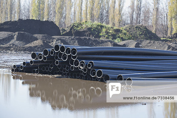 Plastic pipes reflected in water at construction site