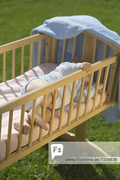 Baby schläft im Kinderbett im Garten