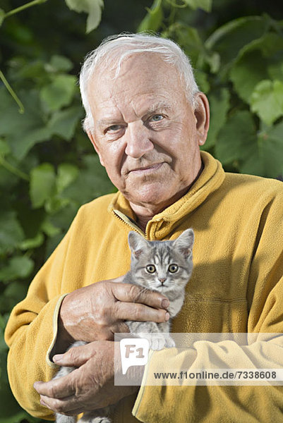 A senior man holding a kitten