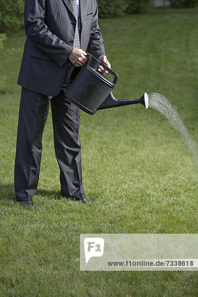 A businessman watering the lawn