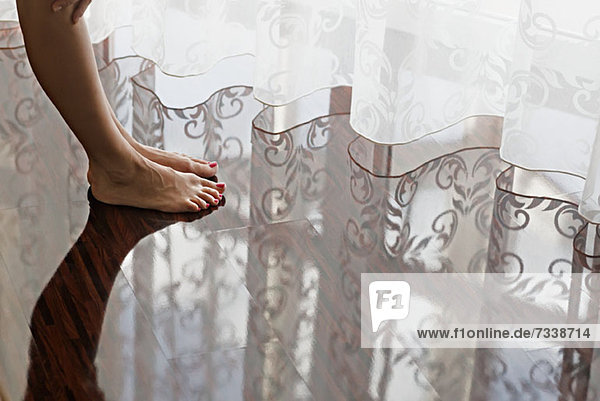 A woman's bare feet on a shiny hardwood floor