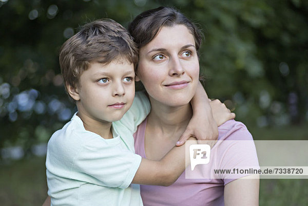 A serene mother and son looking away thoughtfully