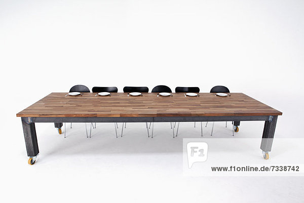 Ein großer Holztisch mit sechs Stühlen und sechs leeren Plätzen