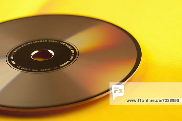 Eine einzelne Compact Disc auf gelbem Hintergrund  Nahaufnahme