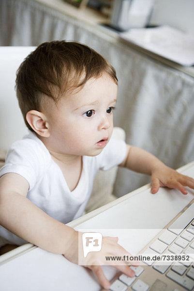 A toddler using a computer keyboard