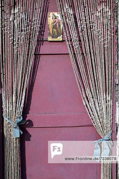 Eine heilige Karte mit der Jungfrau Maria und dem Jesuskind an einer Tür mit Perlenvorhängen.